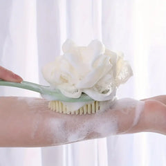 Person using a scrub brush with a loofah on a soapy arm against a white background