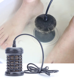Black foot spa device with a person's feet in a basin in the background