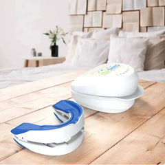 White and blue mouthguard on a wooden surface with a bed and pillows in the background