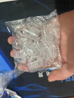 Hand holding a clear plastic bag with small toe protectors against a dark background