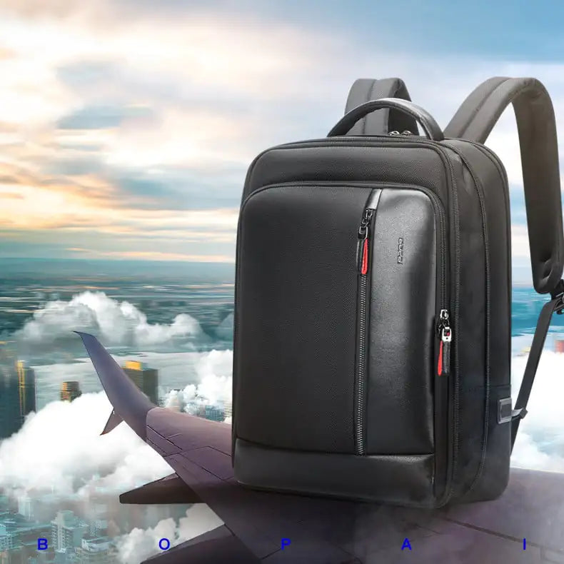 Black backpack with red zipper pull against a cityscape and airplane wing background
