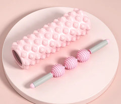 Pink massage roller and balls on a white plate with a pink background