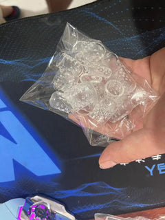 Clear silicone toe protectors in a transparent bag held by a hand against a dark background.
