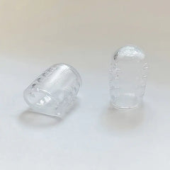 Two clear plastic toe protectors on a white background