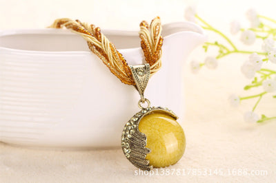 Gold necklace with a yellow pendant on a white background