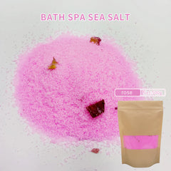 Pink bath spa sea salt with rose petals and a brown packaging bag on a light background.
