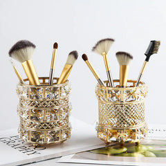 Two decorative makeup brush holders with brushes on a light surface.