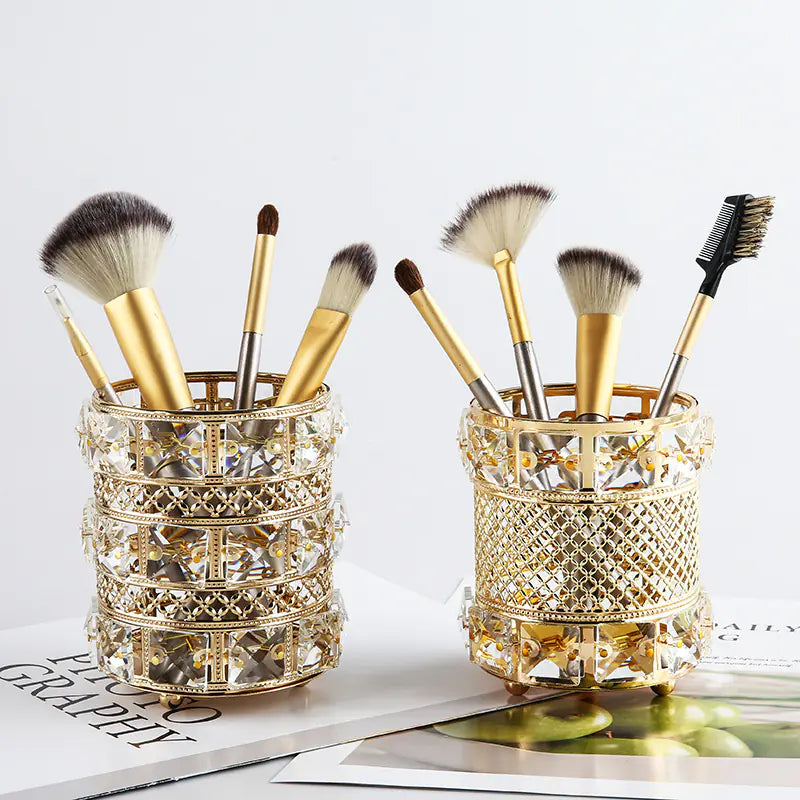 Two decorative makeup brush holders with brushes on a light surface.