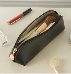 Black makeup pouch with cosmetic items on a light surface