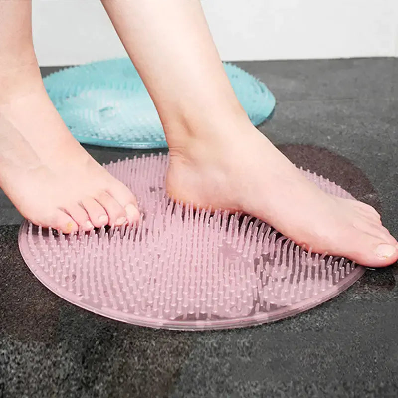Person using a pink foot scrubber mat on a dark surface