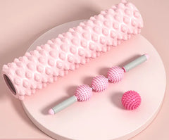 Pink massage roller and balls on a round white plate with a pink background