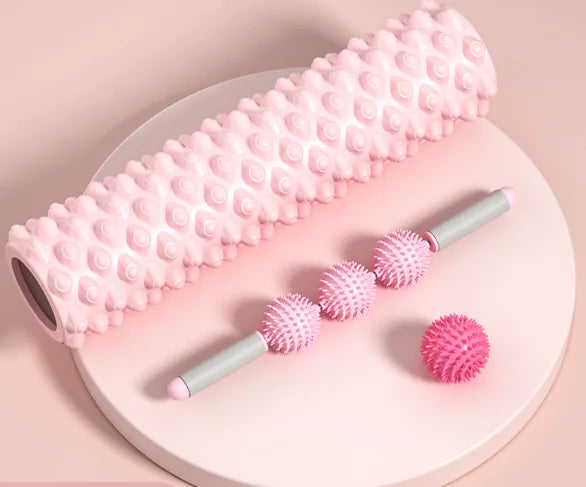 Pink massage roller and balls on a round white plate with a pink background