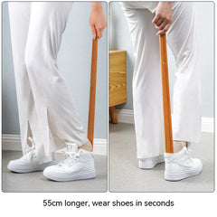 Person using a 55cm long shoehorn to put on white sneakers.