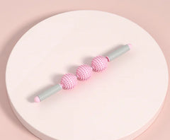 Pink and gray massage tool on a round white platform with a pink background