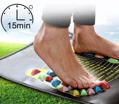 Person using a foot mat with colorful stones on a grassy background