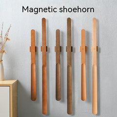 Set of magnetic shoehorns on a gray wall with a vase of dried flowers.