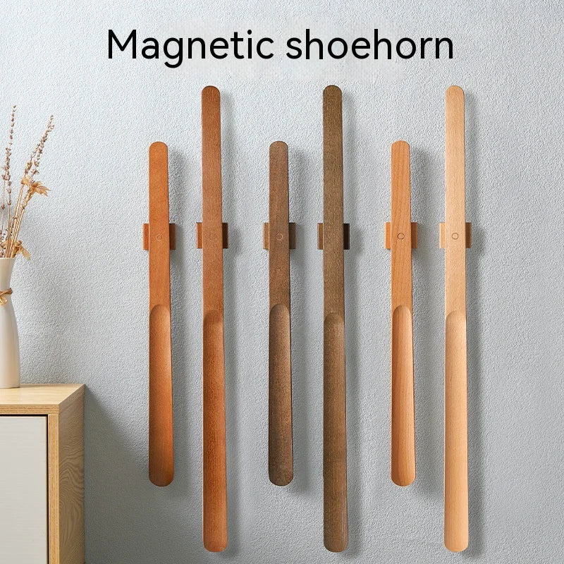 Set of magnetic shoehorns on a gray wall with a vase of dried flowers.