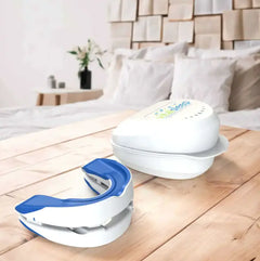Two dental devices, one blue and white, the other white, on a wooden surface with a bedroom background.