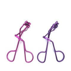 Two pairs of purple and pink eyelash curlers on a white background