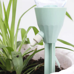 Light green plant watering device with a white bulb attached to a plant.