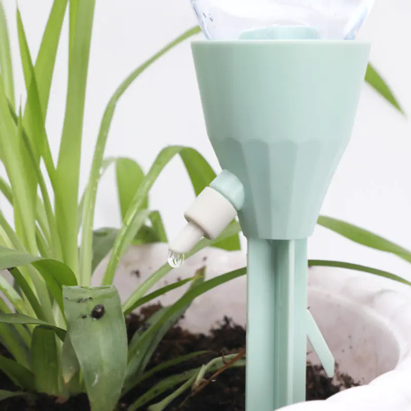 Light green plant watering device with a white bulb attached to a plant.